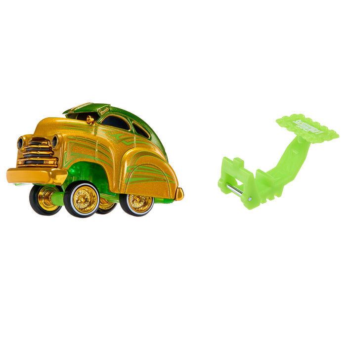 A metallic gold and green toy car shown on a plain white background, alongside a bright green plastic accessory piece.