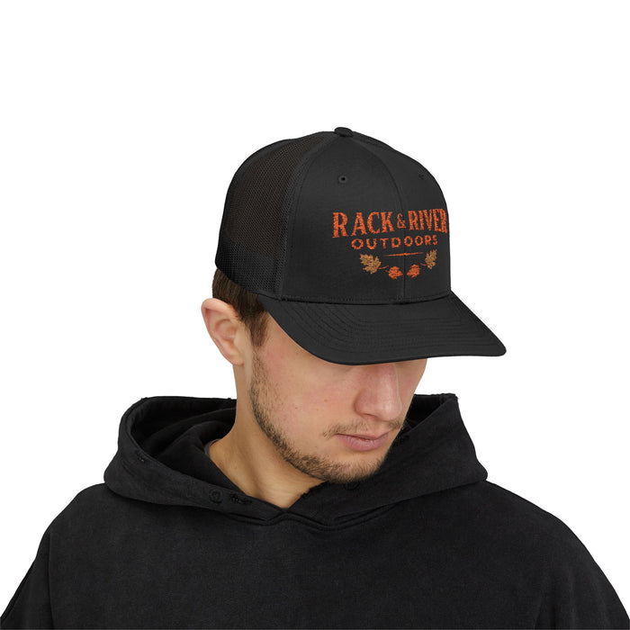 Male model in black Rack & River Outdoors trucker cap with orange embroidered outdoor logo.